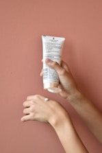 Close-up of hands gently holding natural baby care products with warm cream backgrounds.