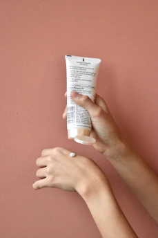 Close-up of hands applying soothing Korean hand cream with floral packaging.