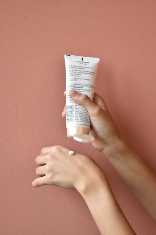 Hands gently holding a small bowl of natural cream, emphasizing care and softness.