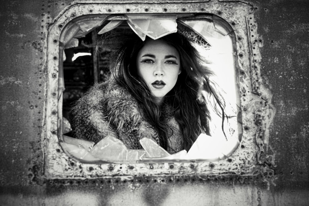 a woman with long hair looking out of a window