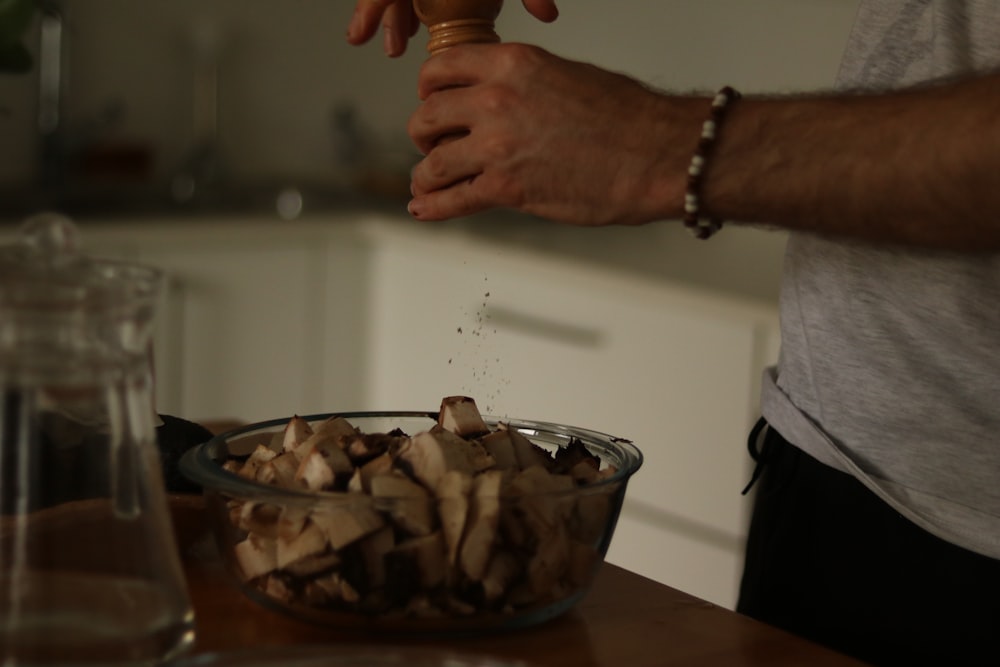 a man is sprinkling mushrooms into a bowl