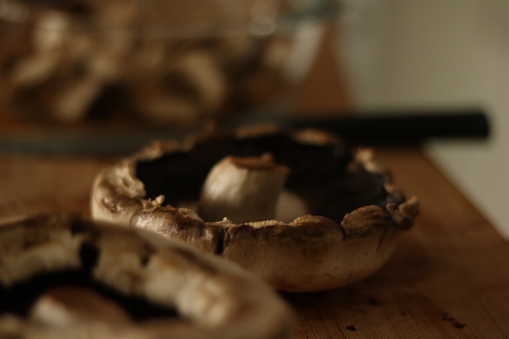 a wooden table topped with a bowl filled with mushrooms