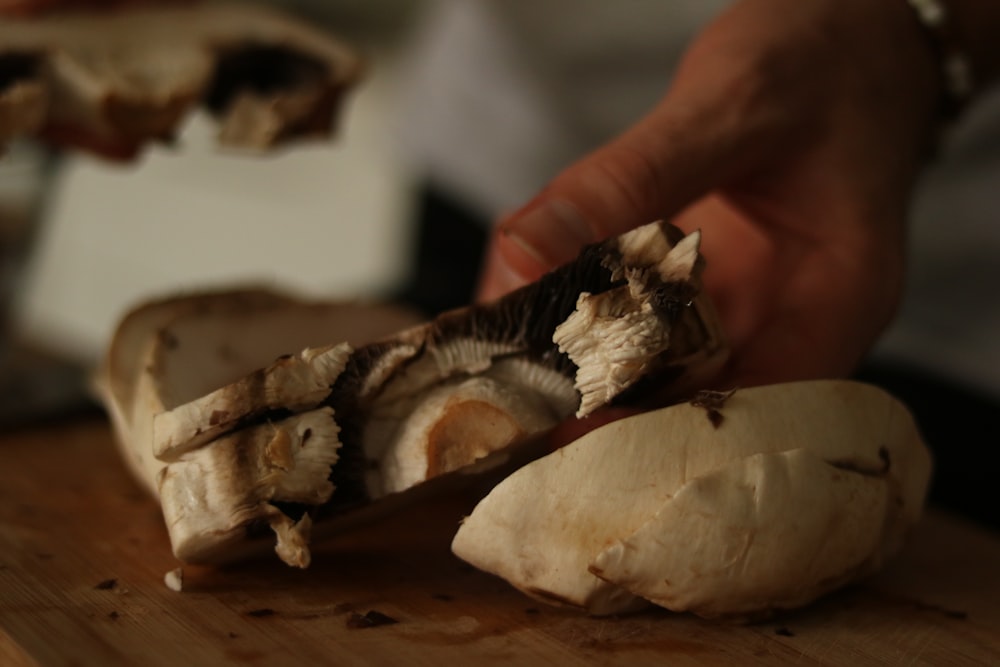 a person slicing a mushroom on a cutting board
