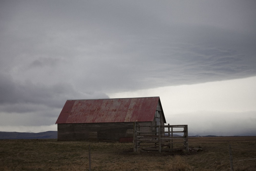 an old barn in a field with a red roof