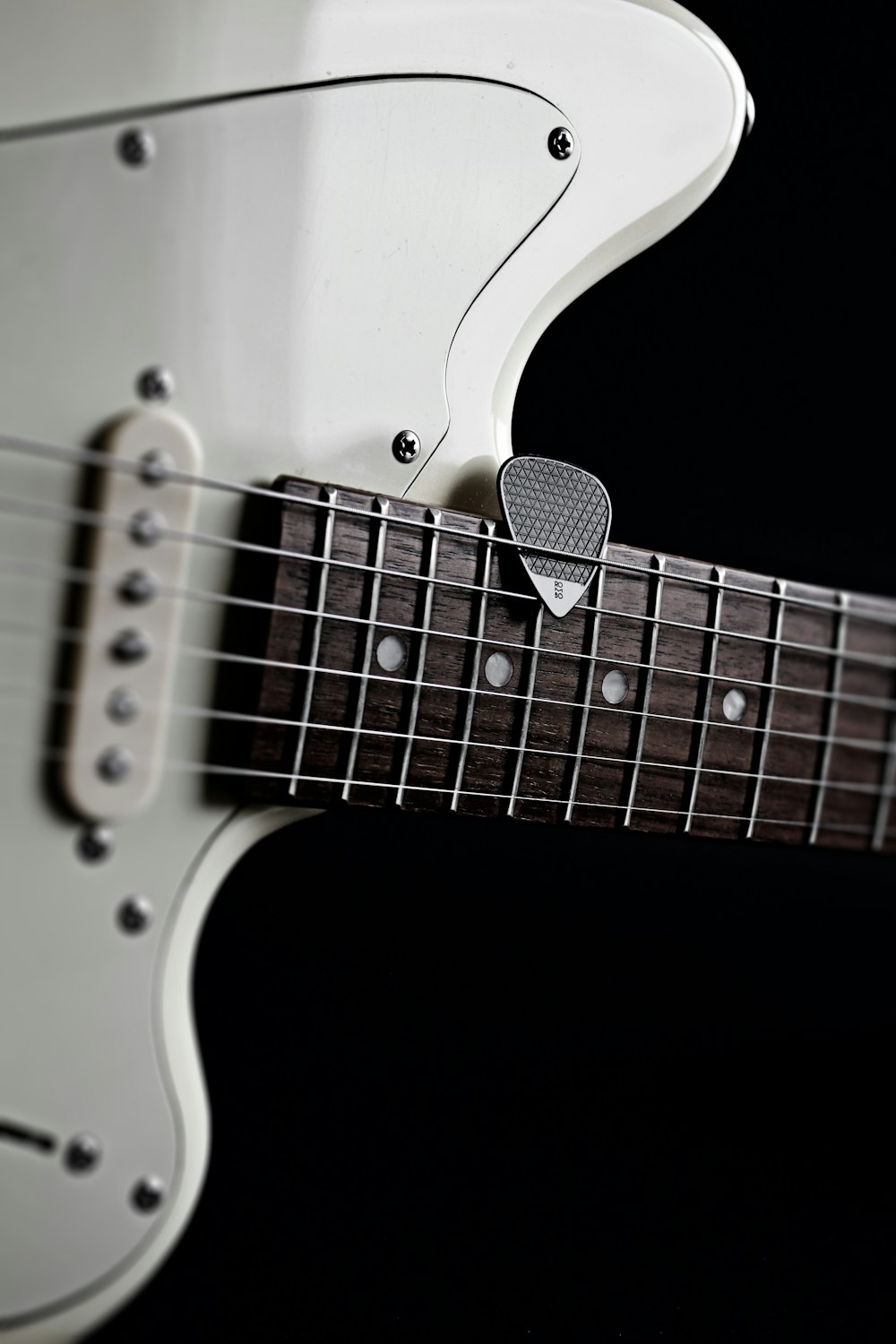 a close up of a guitar neck with a guitar pick