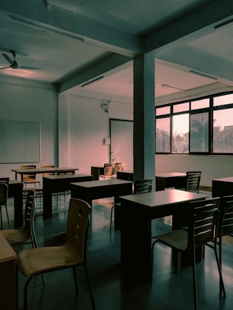 An empty classroom with rows of desks and chairs in late afternoon light, a reminder of what is at stake when school budgets shrink with enrollment