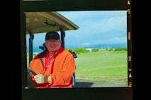 a man in an orange jacket holding a golf club
