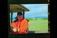 a man in an orange jacket holding a golf club