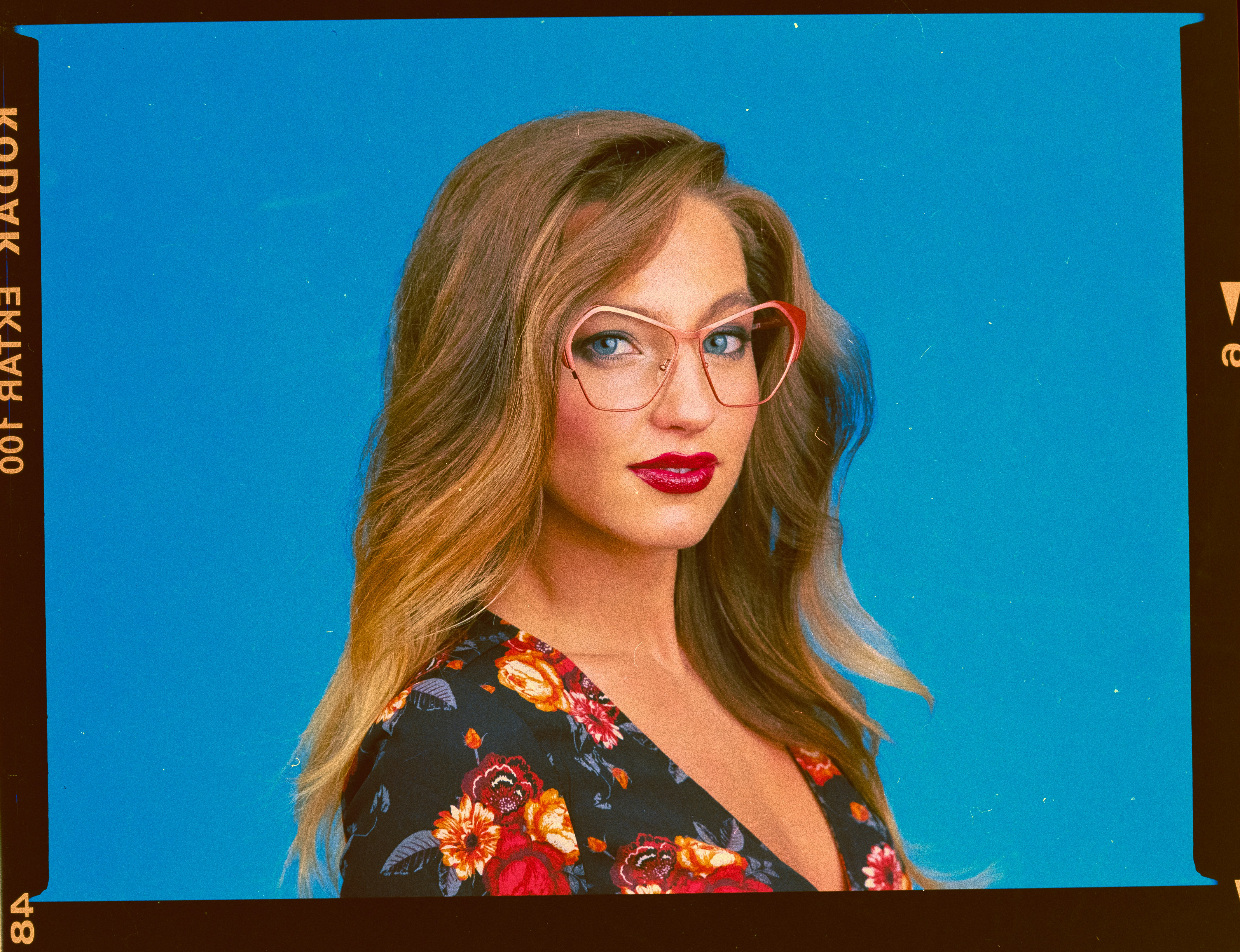 a woman wearing glasses with a blue background
