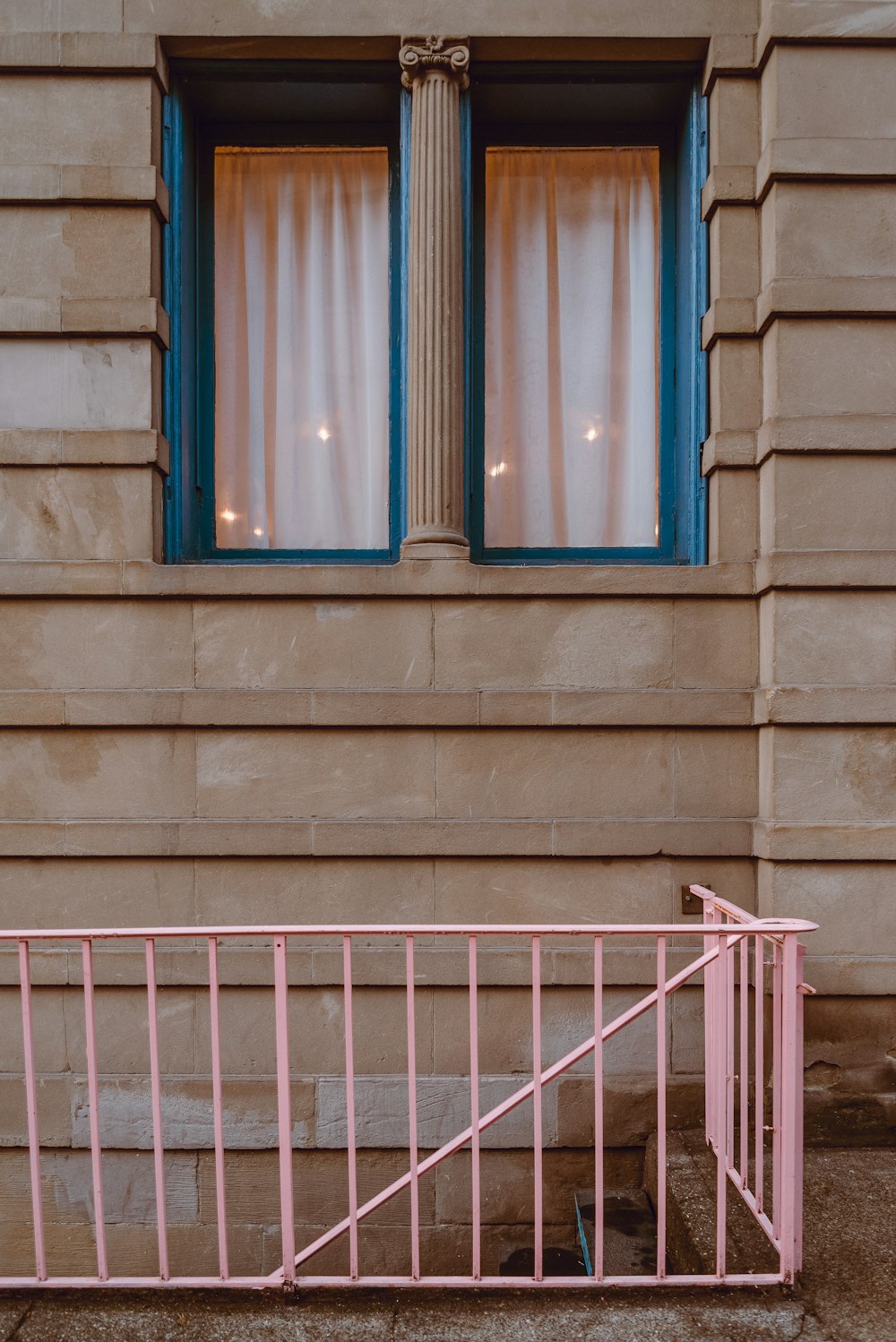 um portão rosa sentado em frente a uma janela