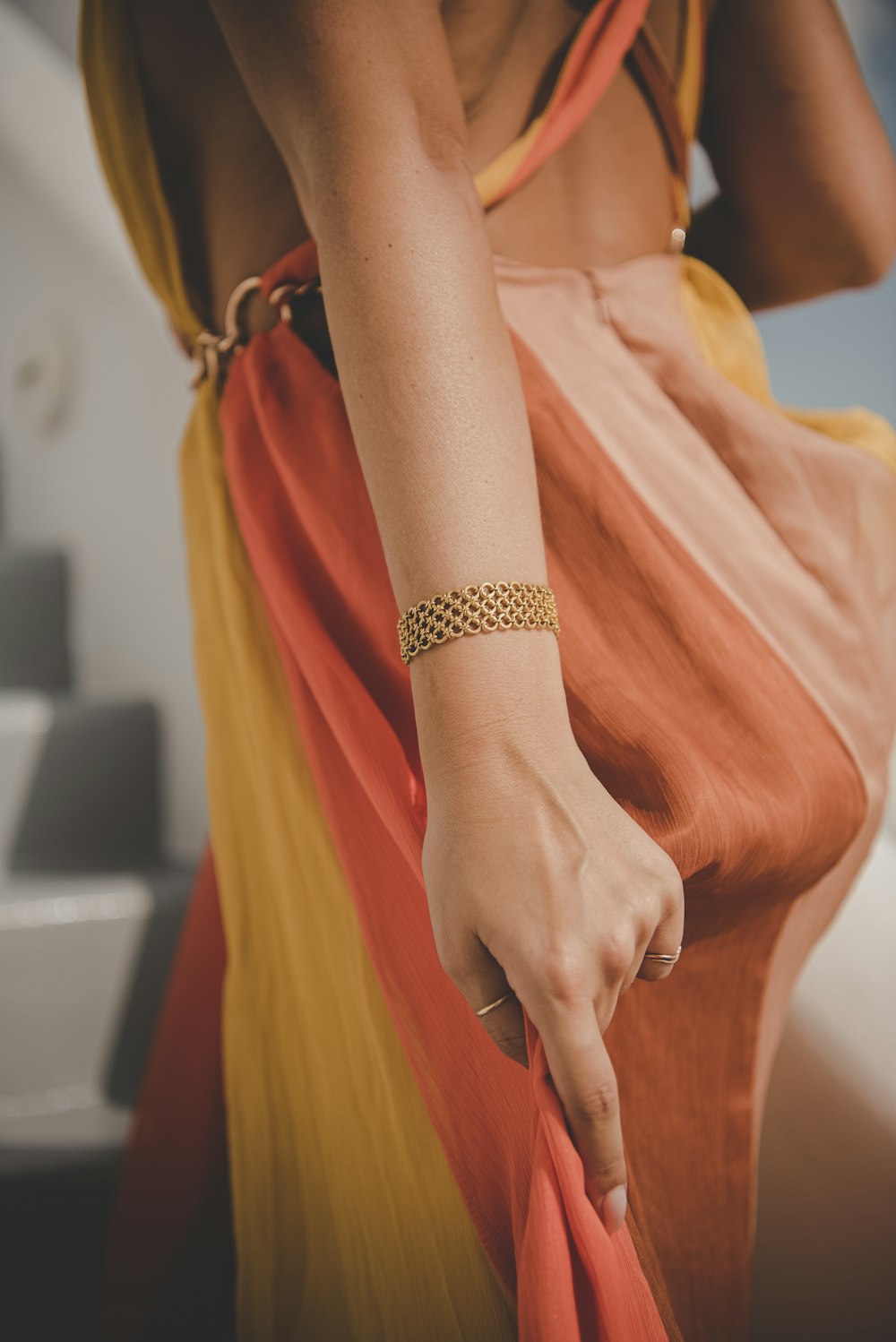 a woman wearing a yellow and orange dress and a bracelet