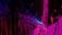 An abstract digital artwork featuring vibrant streaks and splashes of pink, blue, and purple against a predominantly black background. The pattern resembles a chaotic yet structured accumulation of vertical lines and scattered pixels, creating a vivid sense of movement and depth.