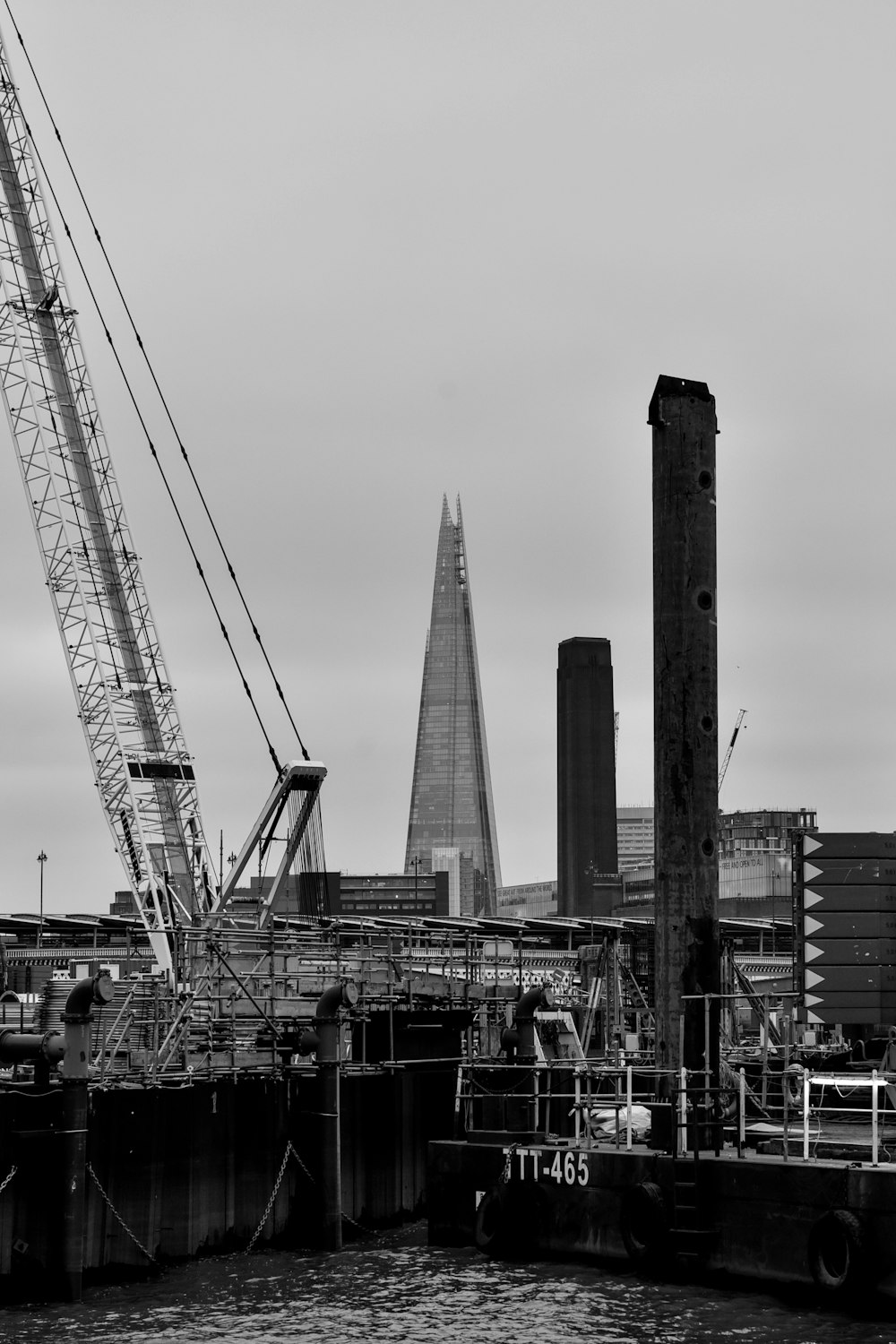 a black and white photo of a crane in a harbor