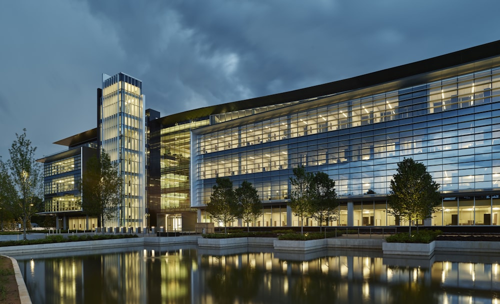 a large glass building sitting next to a body of water