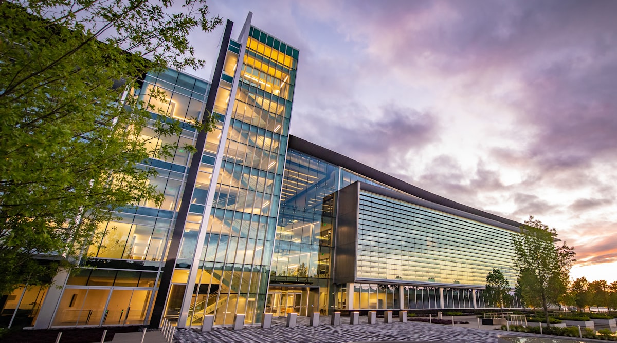 A modern glass office building under a cloudy sky