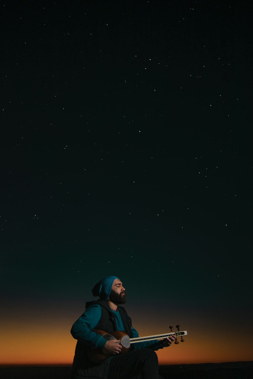 a man sitting on top of a rock under a night sky