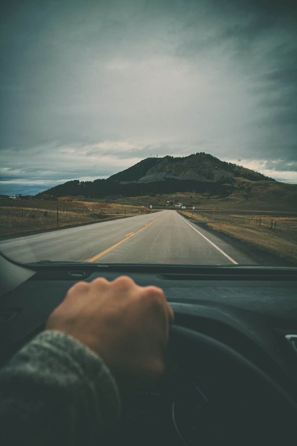 a person driving a car on a road with a mountain in the background