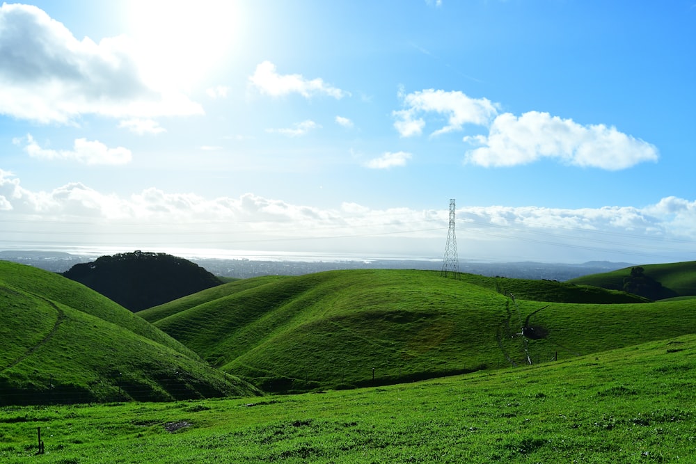 a grassy hill with a telephone tower in the distance