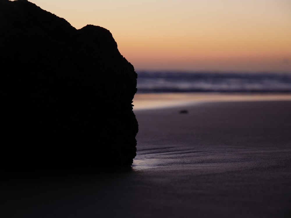 a rock sticking out of the sand on a beach