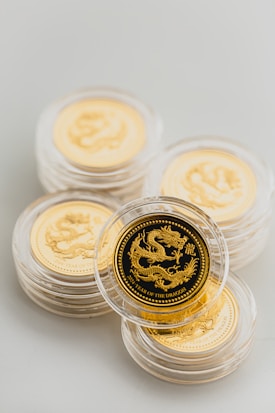 Several gold coins are stacked, each encased in clear protective holders. The coins feature a dragon design and the words 'Year of the Dragon' indicating a commemorative or collectible aspect.