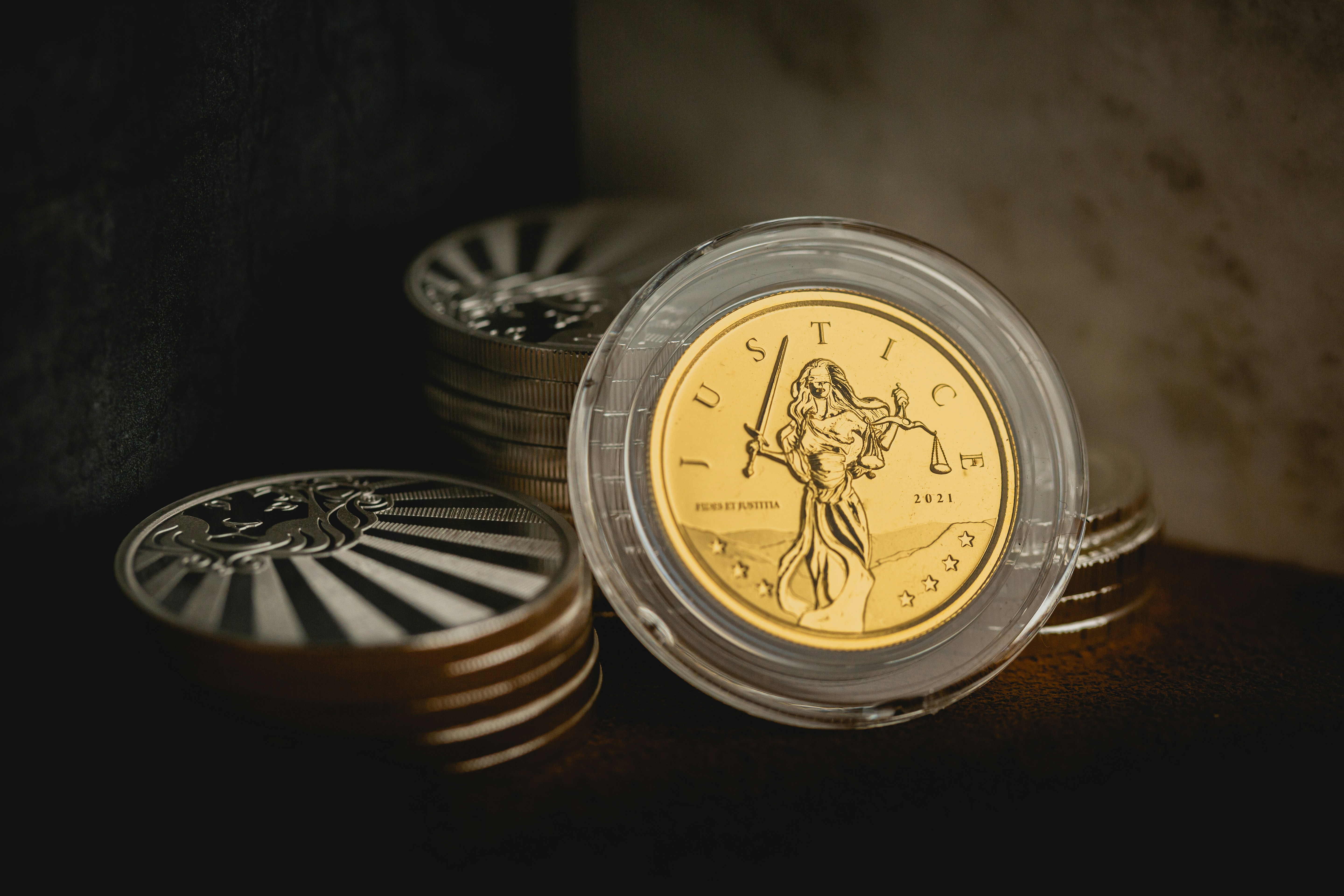 Scottsdale Silver stack of coins, rounds and bars sitting in a pile on a dark background featuring a 2021 Lady Justice Gold coin. Please give a shoutout to Scottsdale Mint if able! Shop online for the most beautiful bullion at ScottsdaleMint.com!