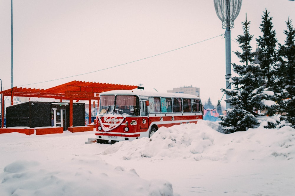 a red and white bus is parked in the snow