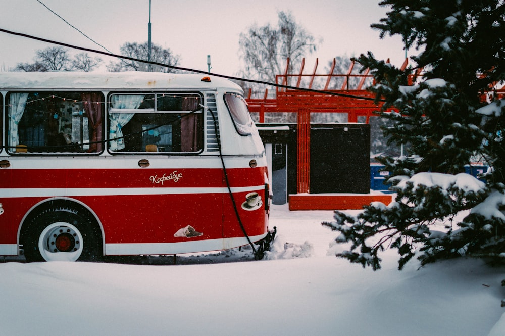 a red and white bus parked in the snow