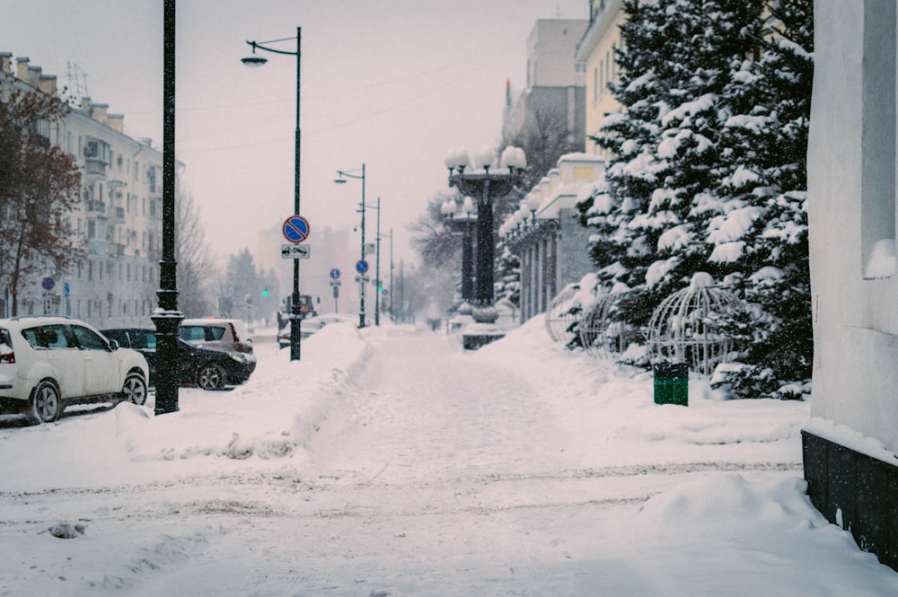 uma rua nevada com carros estacionados ao lado dela