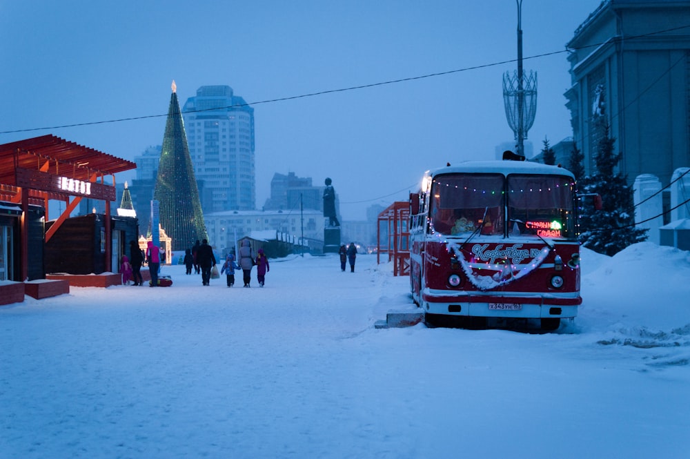 a red and white bus driving down a snow covered street