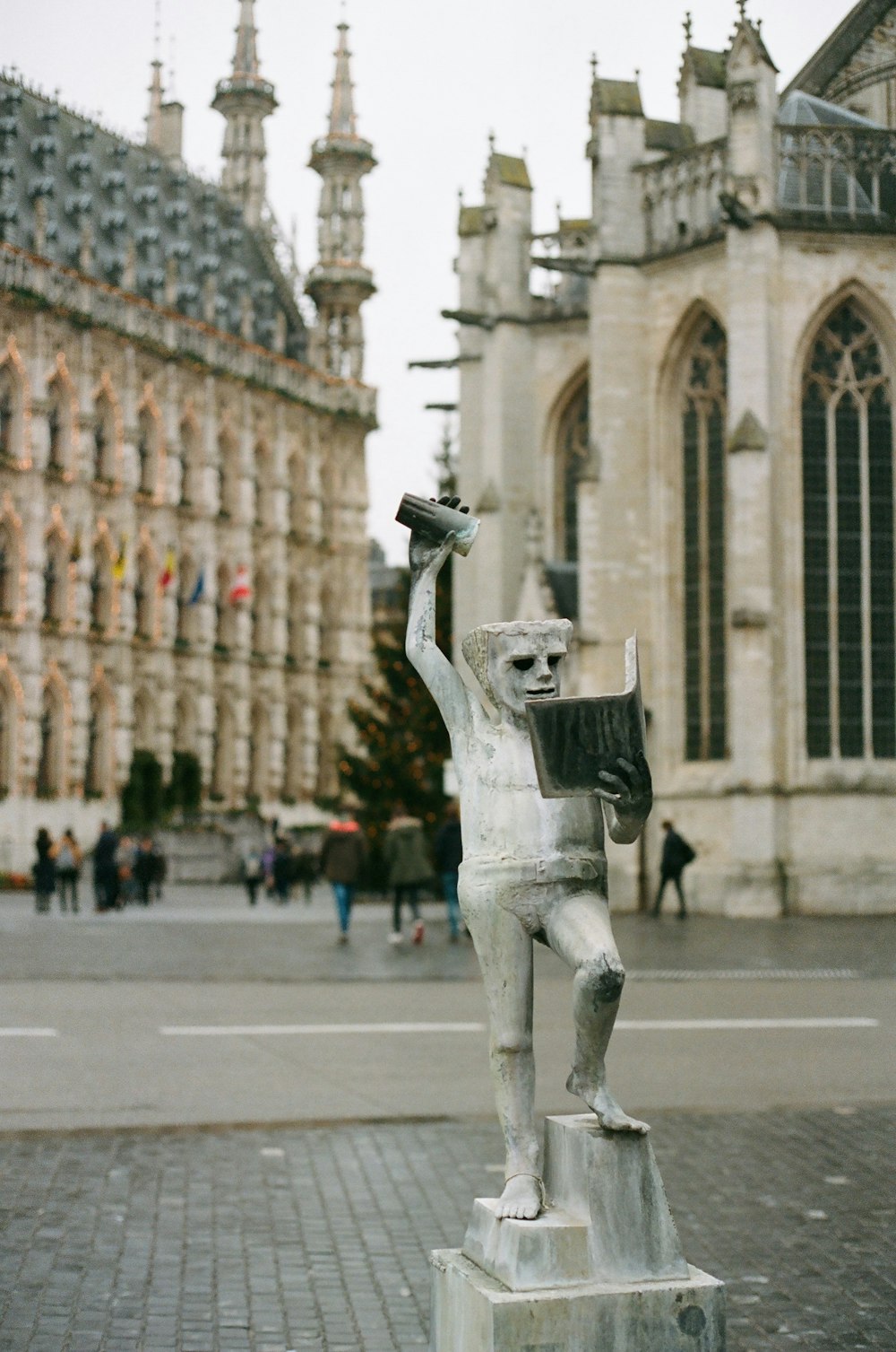 a statue of a man holding a book in front of a building