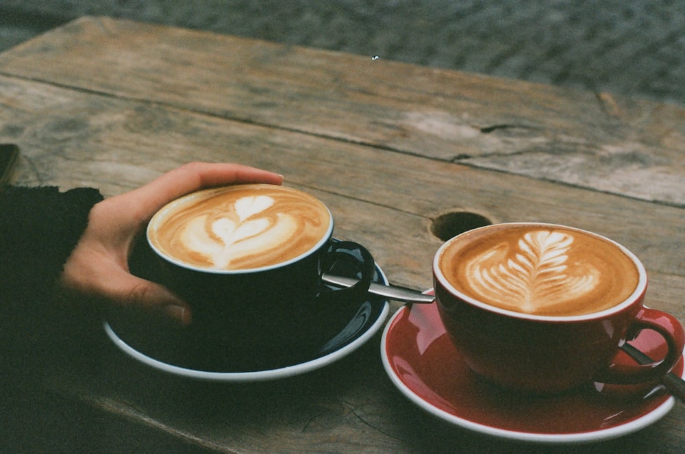 two cups of coffee sitting on top of a wooden table