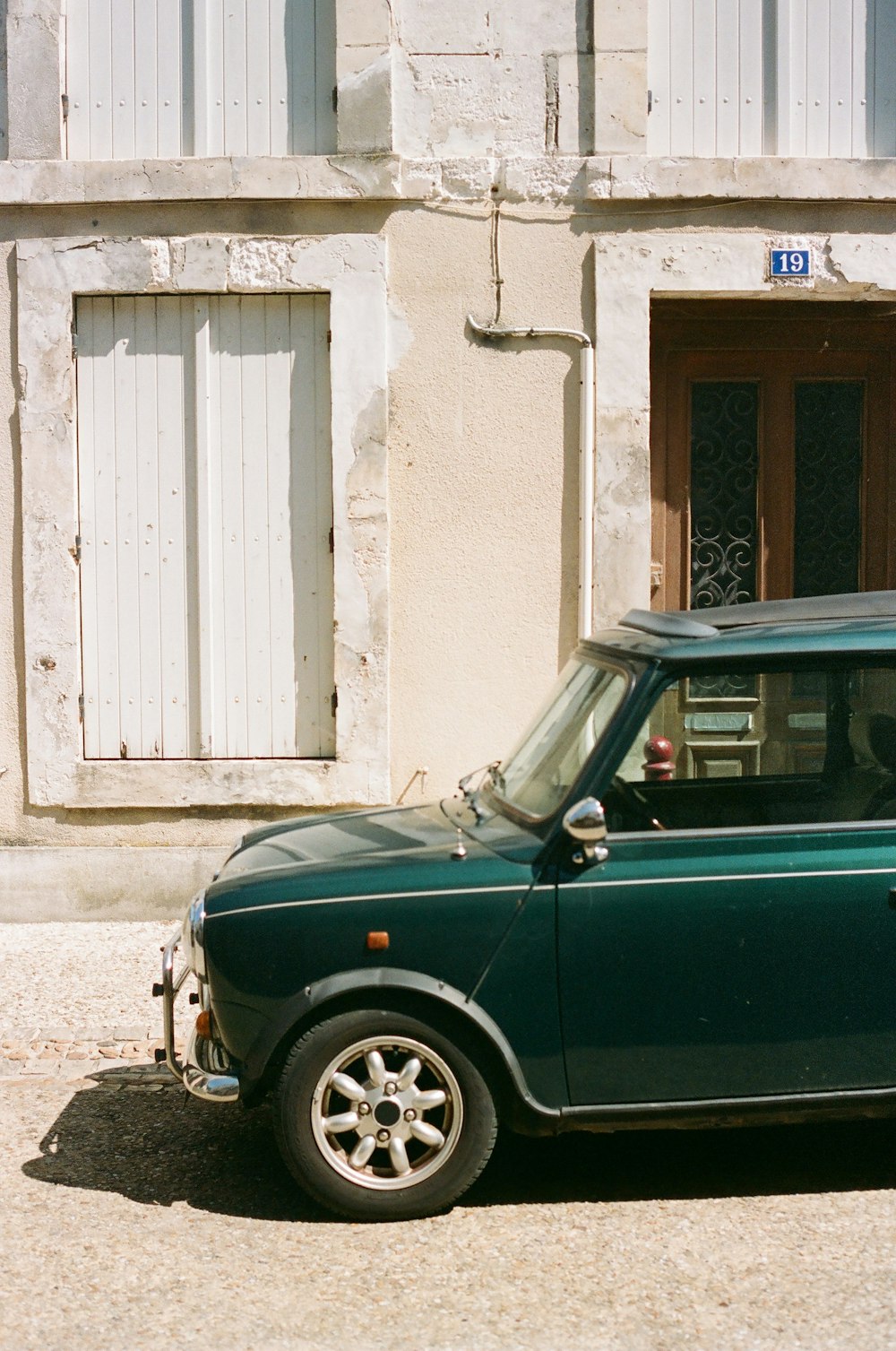 a small green car parked in front of a building