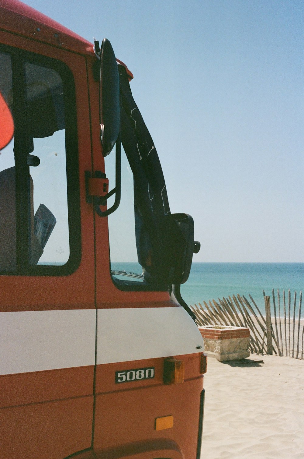 a red truck parked on top of a sandy beach