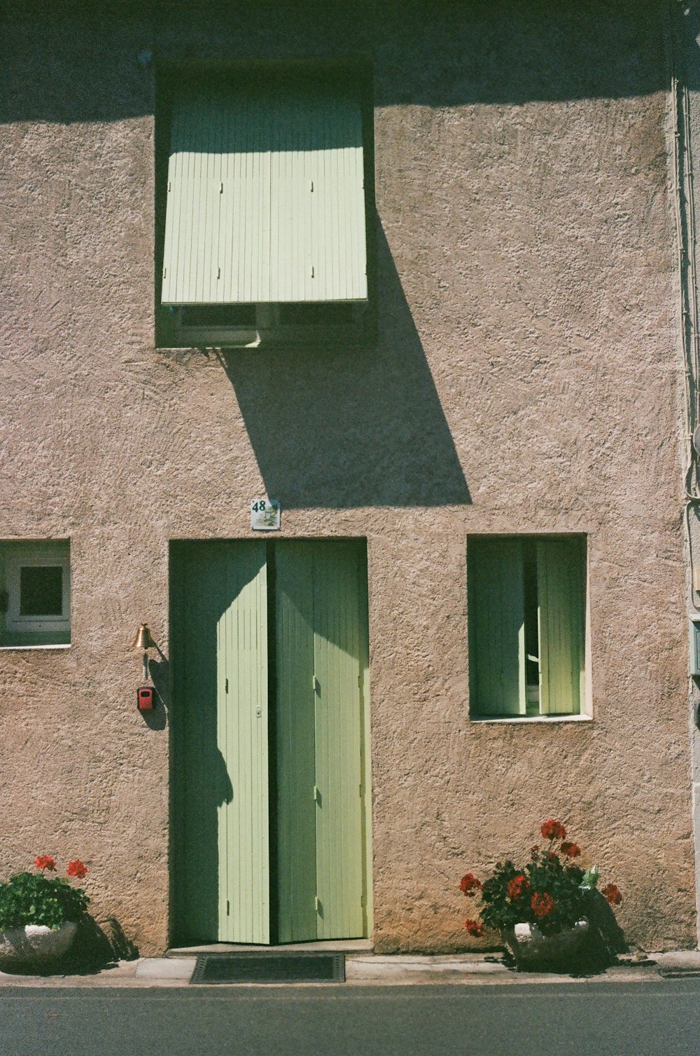 un edificio con dos puertas verdes y una ventana