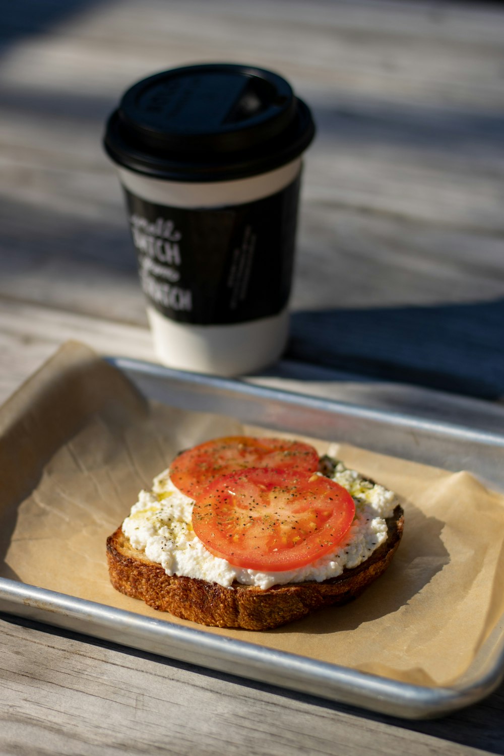 un sándwich tostado con un tomate encima y una taza de café
