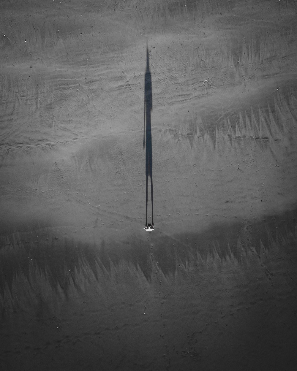 a long shadow of a long pole in the sand