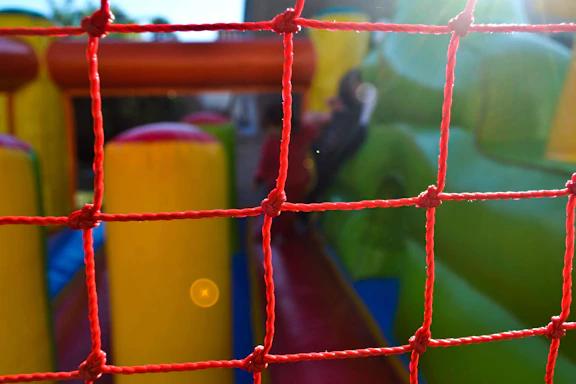 A friendly staff member setting up a colorful inflatable obstacle course in a sunny backyard.