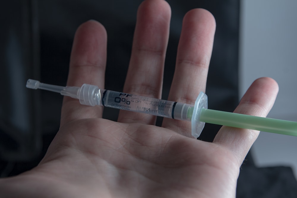 a hand holding a syquet with a needle in it