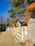 A row of colorful small wooden cabins with stairs leading to heart-shaped doors on their fronts. The cabins are painted in bright colors, including orange, yellow, red, green, and blue. Tall pine trees stand in the background under a clear blue sky.