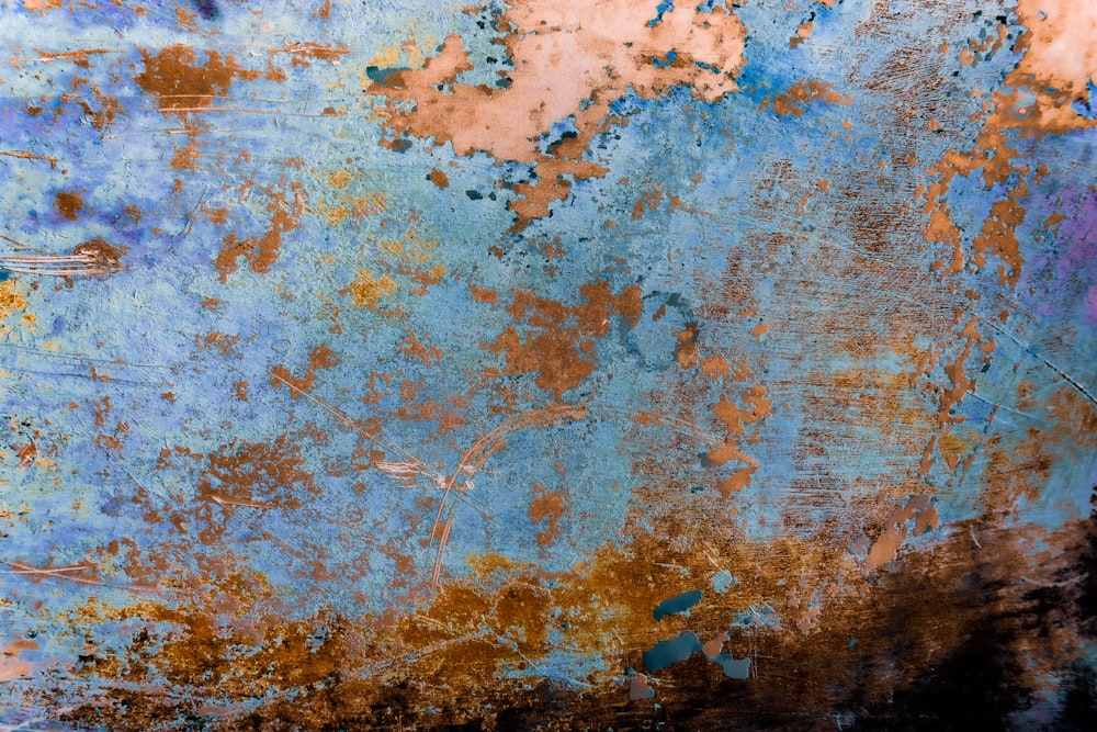 a rusted metal surface with blue and orange paint
