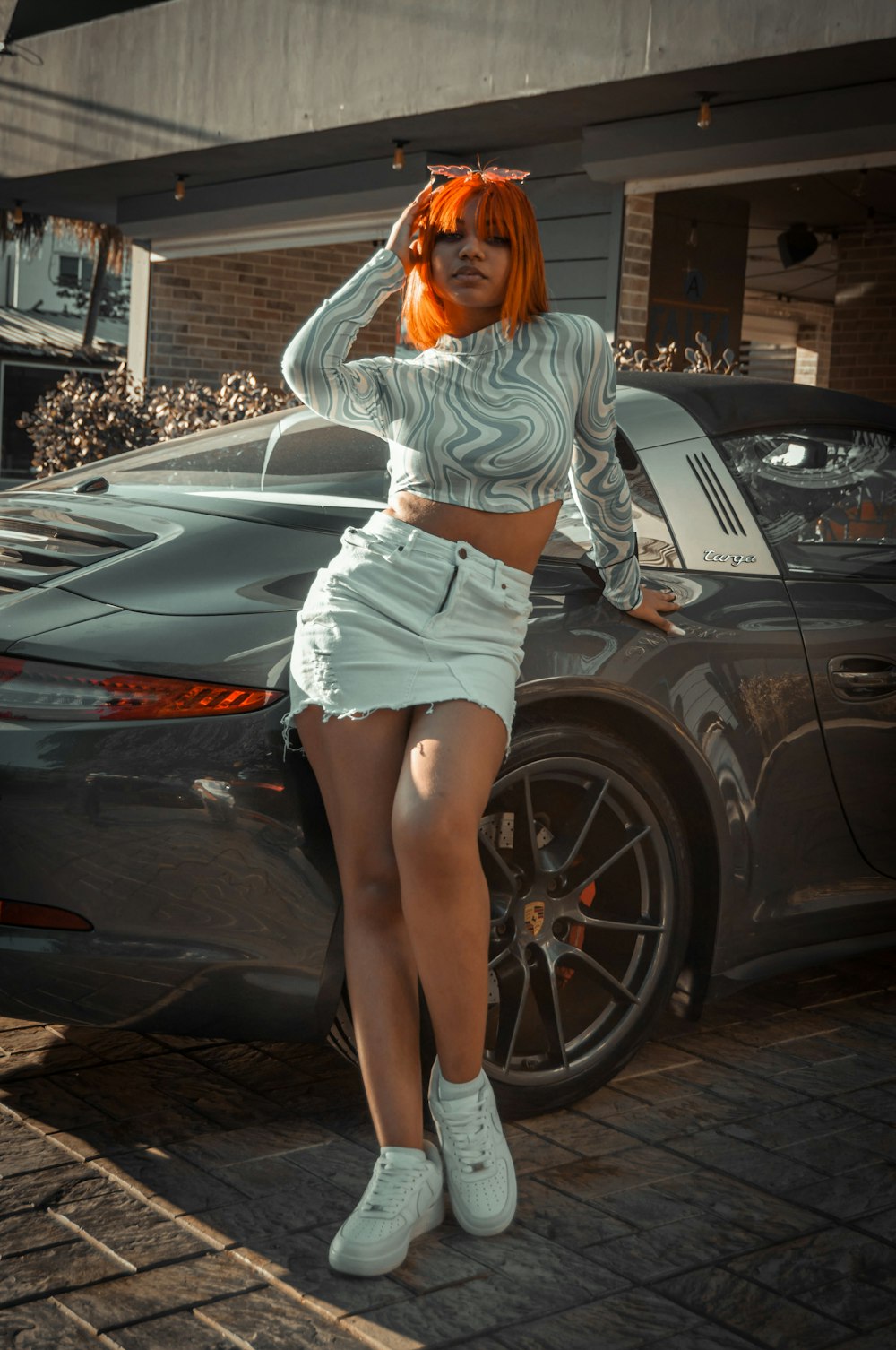 a woman with orange hair standing next to a car