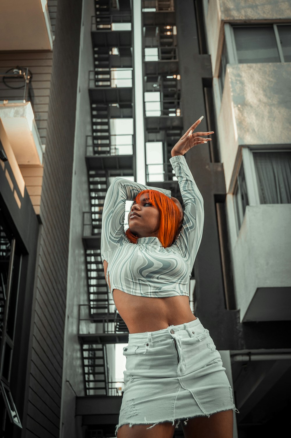 a woman with orange hair standing in front of a tall building