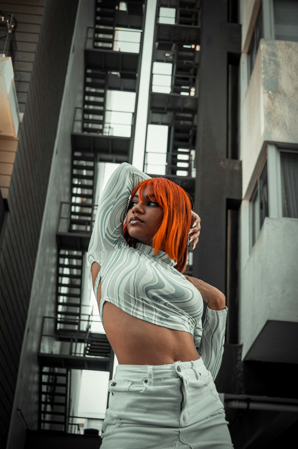 a woman with orange hair is posing in front of a building