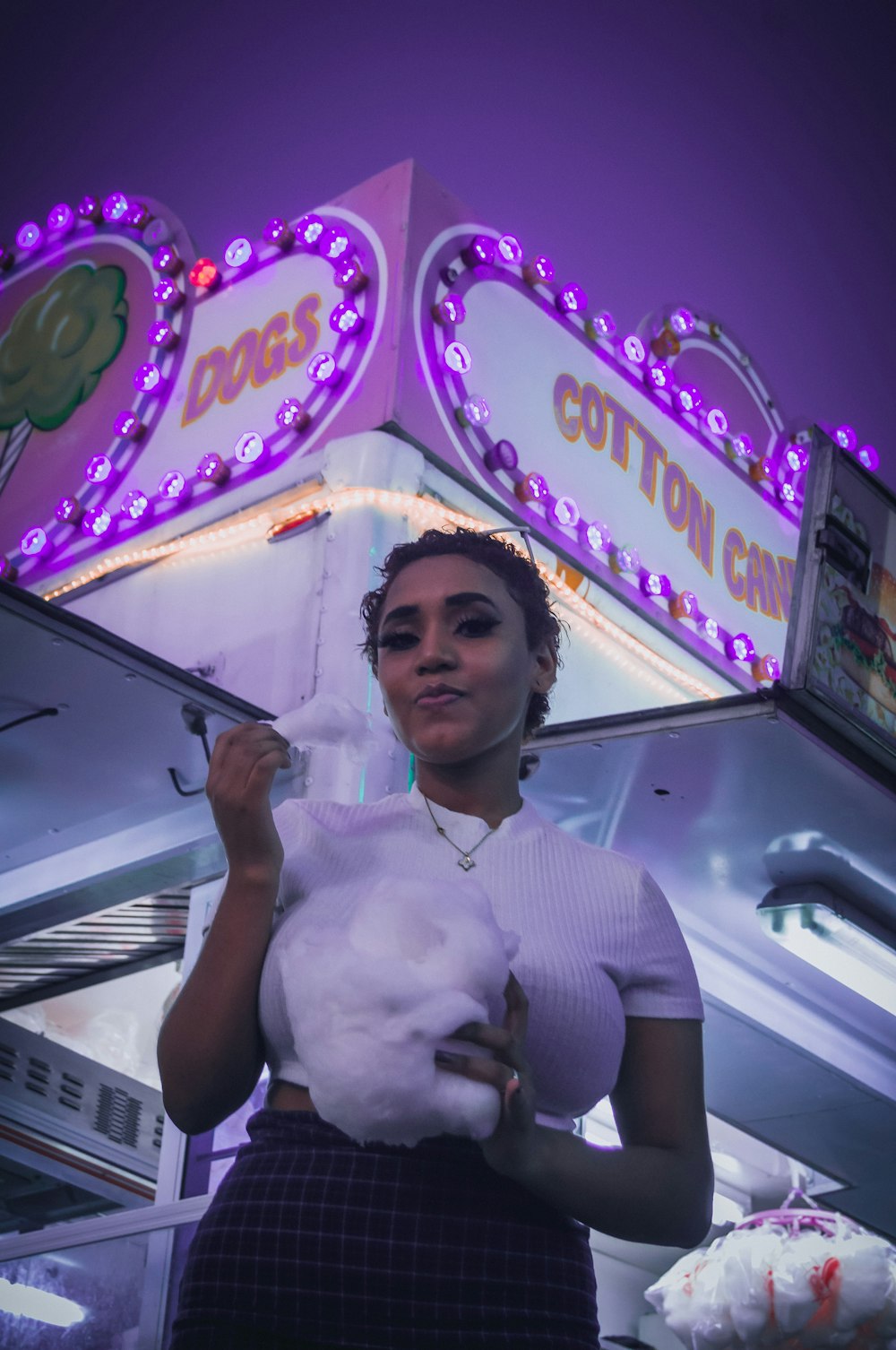 a woman holding a stuffed animal in front of a carnival booth