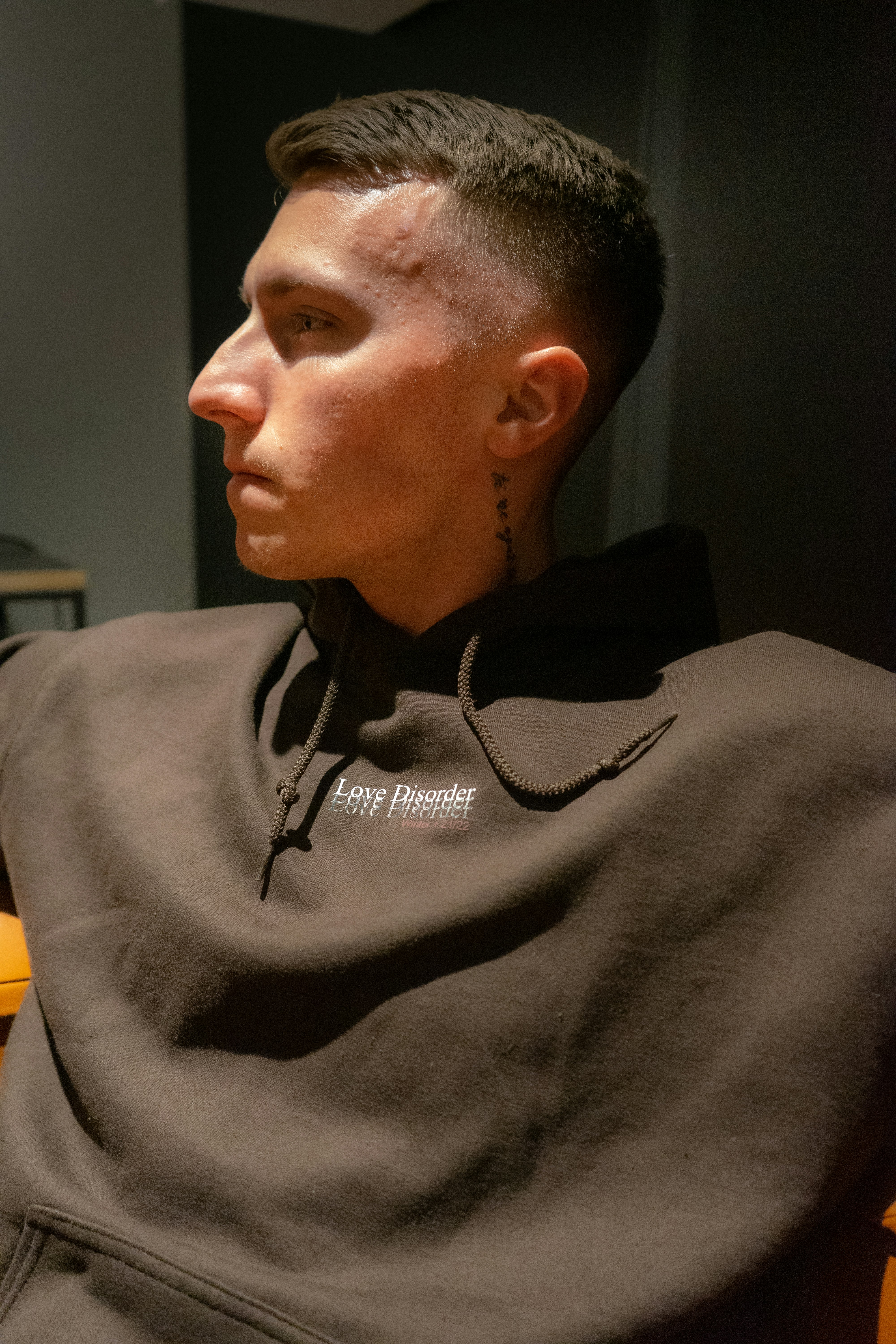 a man sitting in a chair with a tattoo on his neck