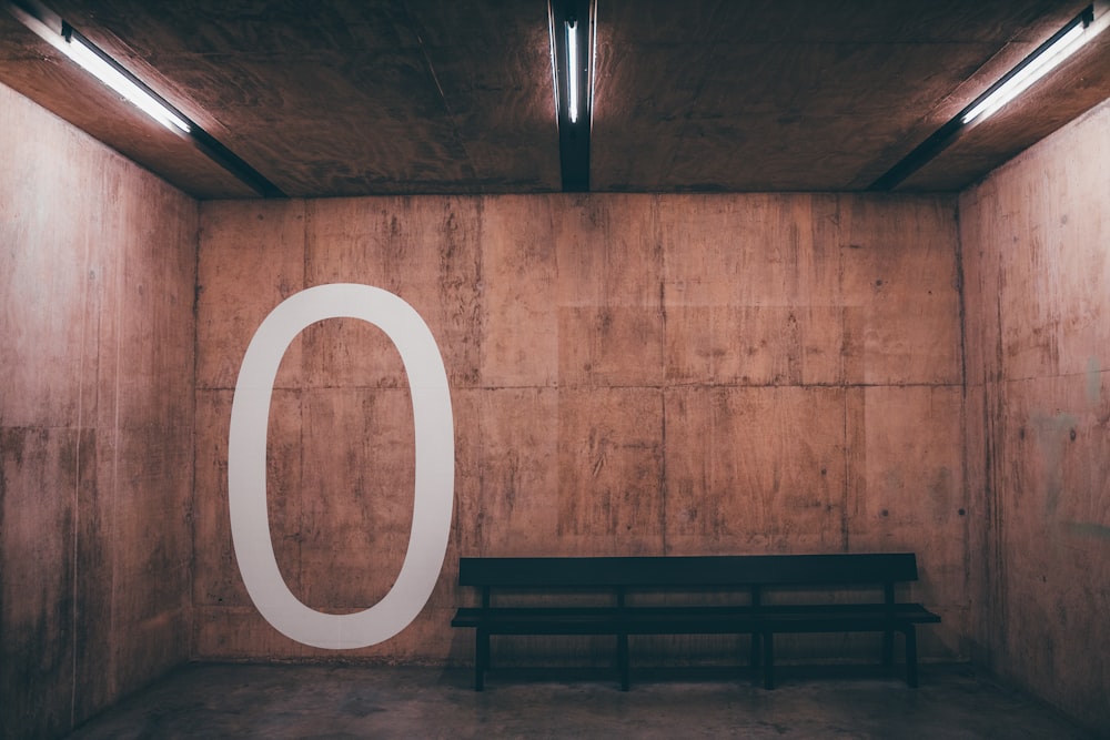 a bench in a room with a large o on the wall