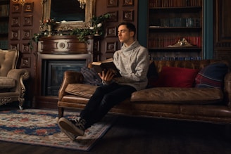 a man sitting on a couch reading a book