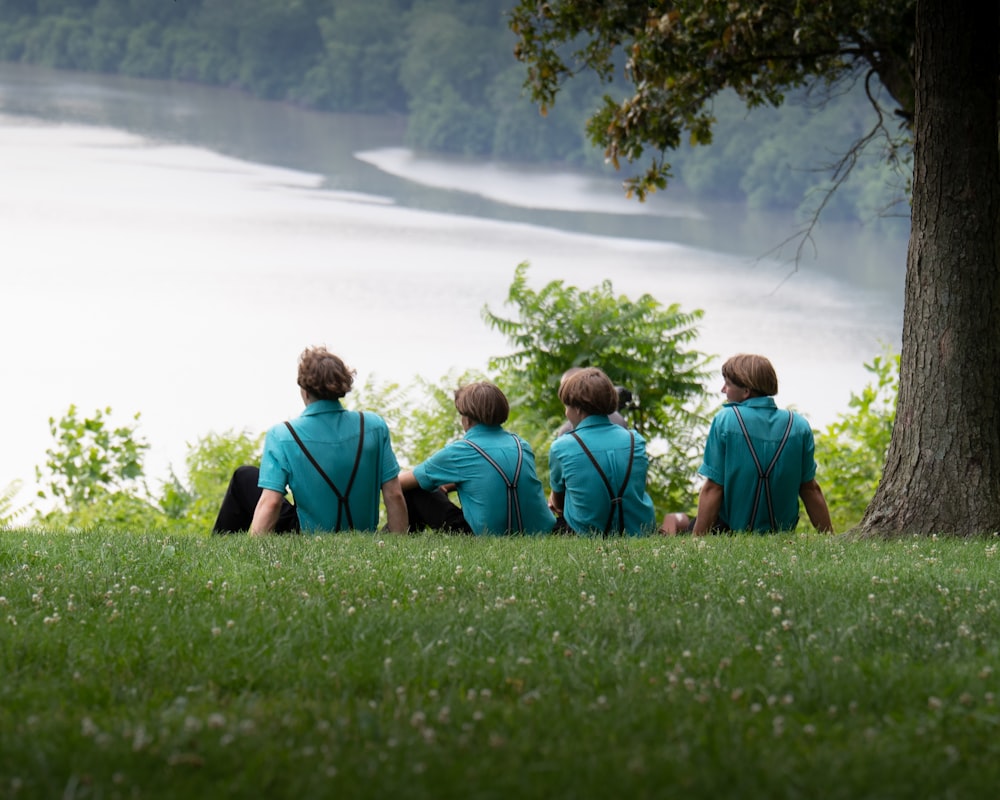 a group of people sitting on top of a lush green field