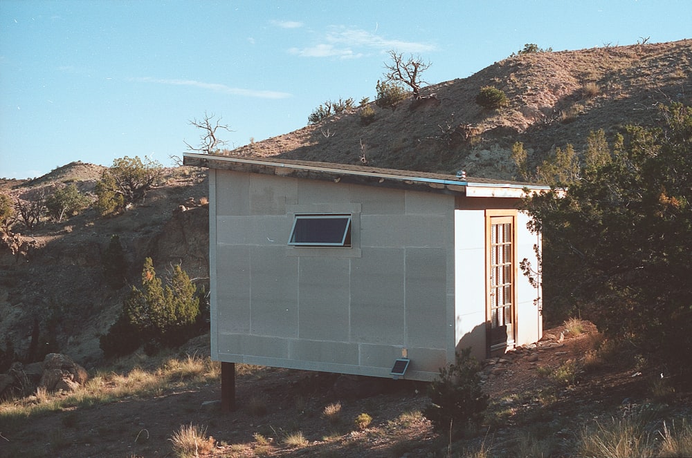 a small outhouse sitting in the middle of a field