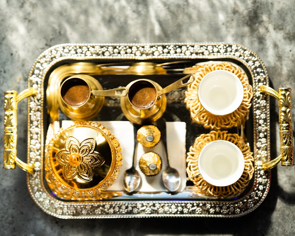 a silver tray topped with gold and white dishes